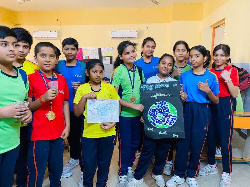 नन्हे बच्चों ने बनाए 'अर्थ क्राउन' कार्यक्रम की शुरुआत नन्हे-मुन्ने बच्चों की रचनात्मक गतिविधियों से हुई। प्राइमरी और यूकेजी के छात्रों ने सुंदर, रंग-बिरंगे 'अर्थ क्राउन' (Crowns) बनाए। इन क्राउन्स को अपने माथे पर सजाकर बच्चे न केवल खुश नजर आए, बल्कि वे पर्यावरण के प्रति अपनी मासूम संवेदनाओं को भी व्यक्त करते दिखे।  विशेष प्रार्थना सभा और बीजारोपण कक्षा 1 से 5 तक के विद्यार्थियों द्वारा एक विशेष प्रार्थना सभा का आयोजन किया गया। इस अवसर पर विद्यालय की प्रधानाचार्या डॉ. रीना पाठक ने छात्रों को संबोधित करते हुए कहा कि पृथ्वी की सुरक्षा और संरक्षण हमारी सर्वोच्च प्राथमिकता होनी चाहिए। उन्होंने बच्चों को प्रेरित किया कि वे प्रकृति के साथ तालमेल बनाकर रहें।  शपथ ग्रहण: छात्रों ने सामूहिक रूप से पृथ्वी को हरा-भरा और सुरक्षित बनाए रखने की शपथ ली।  बीजारोपण: भविष्य की हरियाली के लिए नन्हे हाथों ने मिट्टी में बीज रोपकर एक नई शुरुआत की।  रचनात्मकता के जरिए संरक्षण का संदेश कक्षा 6 से 12 तक के विद्यार्थियों ने भी इस मुहिम में बढ़-चढ़कर हिस्सा लिया। कार्यक्रम में आकर्षण का मुख्य केंद्र रहे:  वेस्ट टू बेस्ट: पुराने समाचार पत्रों से बने आकर्षक थैलों का प्रदर्शन कर प्लास्टिक मुक्त जीवन का संदेश दिया गया।  प्रेरक उक्तियां: पोस्टर और नारों के माध्यम से पर्यावरण संरक्षण की महत्ता बताई गई।  लघु नाटिका एवं परिचर्चा: छात्रों ने नुक्कड़ नाटक और चर्चा के जरिए पृथ्वी को प्रदूषित होने से बचाने के उपाय साझा किए।