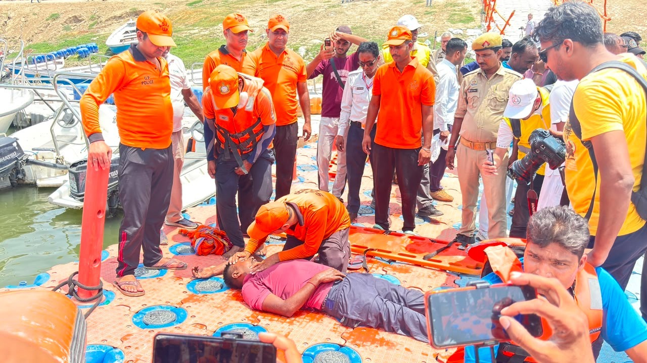 44 संवेदनशील जिलों की 118 तहसीलों में एक साथ चला अभियान उत्तर प्रदेश के उन 44 जनपदों को इस अभ्यास के लिए चुना गया था, जो भौगोलिक रूप से हर साल बाढ़ या जलभराव की मार झेलते हैं।  बलों की भारी तैनाती: इन जिलों की कुल 118 तहसीलों में राहत बलों ने अपनी कार्यकुशलता का प्रदर्शन किया। इस राज्यस्तरीय अभ्यास में पीएसी (PAC) की 17 वाहिनियों से 7 कंपनियां और 1 प्लाटून के जवान शामिल हुए।  एसडीआरएफ की मुस्तैदी: इसके साथ ही राज्य आपदा मोचन बल (SDRF) की 16 अत्याधुनिक टीमों ने भी अलग-अलग मोर्चों पर कमान संभाली।  नाव संचालन से लेकर रेस्क्यू ऑपरेशन तक: हर तकनीक की हुई जांच मॉक ड्रिल के दौरान नदियों और जलमग्न क्षेत्रों के कृत्रिम दृश्य तैयार कर असल रेस्क्यू ऑपरेशन जैसी चुनौतियों का सामना किया गया। इस दौरान जवानों ने निम्नलिखित प्रमुख तकनीकों और उपकरणों का लाइव परीक्षण किया:  आधुनिक नाव संचालन: बाढ़ की तेज लहरों के बीच मोटर बोट और लाइफ-बोट्स को सुरक्षित ढंग से चलाने का अभ्यास।  सुरक्षित निकासी (Evacuation): जलमग्न या पूरी तरह से डूब चुके गांवों और घरों से बुजुर्गों, महिलाओं और बच्चों को सुरक्षित निकालकर राहत शिविरों तक पहुंचाना।  हाई-टेक उपकरणों का परीक्षण: लाइफ जैकेट, लाइफ बॉय, आधुनिक रस्सियों के माध्यम से वर्टिकल रेस्क्यू, और पानी के भीतर काम आने वाले आधुनिक जीवनरक्षक उपकरणों की उपलब्धता व कार्यशीलता को जांचा गया।  प्राथमिक उपचार (First Aid): पानी से निकाले गए पीड़ितों को अस्पताल पहुंचाने से पहले दिए जाने वाले तत्काल मेडिकल सपोर्ट (CPR और फर्स्ट एड) का भी प्रदर्शन किया गया।  विभिन्न विभागों का दिखा समेकित तालमेल आपदा के समय सबसे महत्वपूर्ण कड़ी विभिन्न विभागों के बीच का आपसी समन्वय (Coordination) होता है। इस मॉक एक्सरसाइज में केवल सुरक्षा बल ही नहीं, बल्कि जिला प्रशासन, स्थानीय पुलिस, स्वास्थ्य विभाग, राजस्व विभाग (लेखपाल/कानूनगो), अग्निशमन सेवा (Fire Brigade), एनडीआरएफ (NDRF), और विभिन्न स्वयंसेवी संस्थाओं (NGOs) ने मिलकर काम किया। सभी विभागों ने एकजुट होकर 'समेकित आपदा प्रबंधन कार्यप्रणाली' का बेहतरीन उदाहरण पेश किया।  "मानव जीवन की सुरक्षा हमारी सर्वोच्च प्राथमिकता" &mdash; डीजीपी पीएसी सफल आयोजन के बाद पुलिस महानिदेशक (PAC) आलोक सिंह ने बाढ़ राहत दलों और एसडीआरएफ की टीमों को कड़े और स्पष्ट निर्देश जारी किए:  "बाढ़ राहत दलों के सभी कार्मिकों की नियमित ब्रीफिंग की जाए। सभी मोटर बोट्स और जीवनरक्षक उपकरणों का समय-समय पर निरीक्षण और मेंटेनेंस होना अनिवार्य है, ताकि जब भी आपात स्थिति आए, तो प्रभावित क्षेत्रों में बिना एक मिनट गंवाए तत्काल राहत कार्य शुरू किया जा सके। मानव जीवन की सुरक्षा हमारी सर्वोच्च प्राथमिकता है। उत्तर प्रदेश के नागरिकों की सुरक्षा और सहायता के लिए पीएसी और एसडीआरएफ का हर एक जवान पूर्ण प्रतिबद्धता के साथ 24 घंटे मुस्तैद है।"